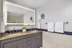 Een moderne badkamer met een grote spiegel, twee wasbakken en een handdoekrek.
