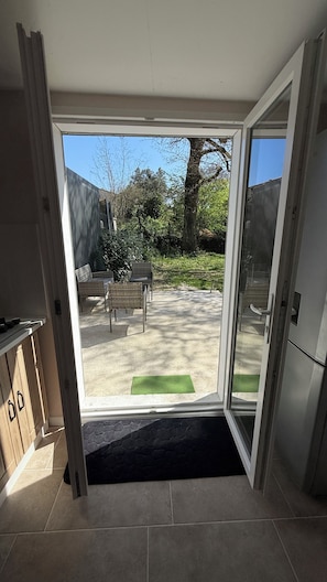 Quarto com porta de vidro deslizante para um pátio externo com banco e cadeiras.
