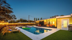 Un jardin avec une piscine, des chaises longues et un patio couvert.
