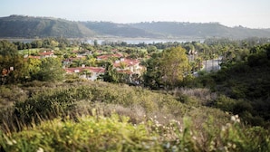 A residential area with houses featuring red-tiled roofs, surrounded by lush greenery and hills in the background. - Four Seasons Residence Aviara (Carlsbad)