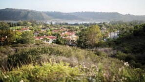Ein Wohngebiet mit Häusern und roten Ziegeldächern, umgeben von üppigem Grün und Hügeln im Hintergrund.