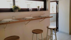 A kitchen with a wooden countertop, two stools, and a window with potted plants. - Cozy and spacious apartment in the heart of the historic center of Catania (Catania)