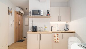Eine kompakte Küchenzeile mit Mikrowelle, Kaffeemaschine und kleinem Spülbecken.
