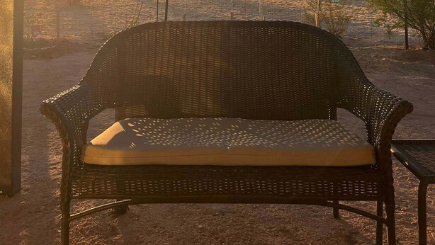 A wicker bench under string lights with a sunset view.