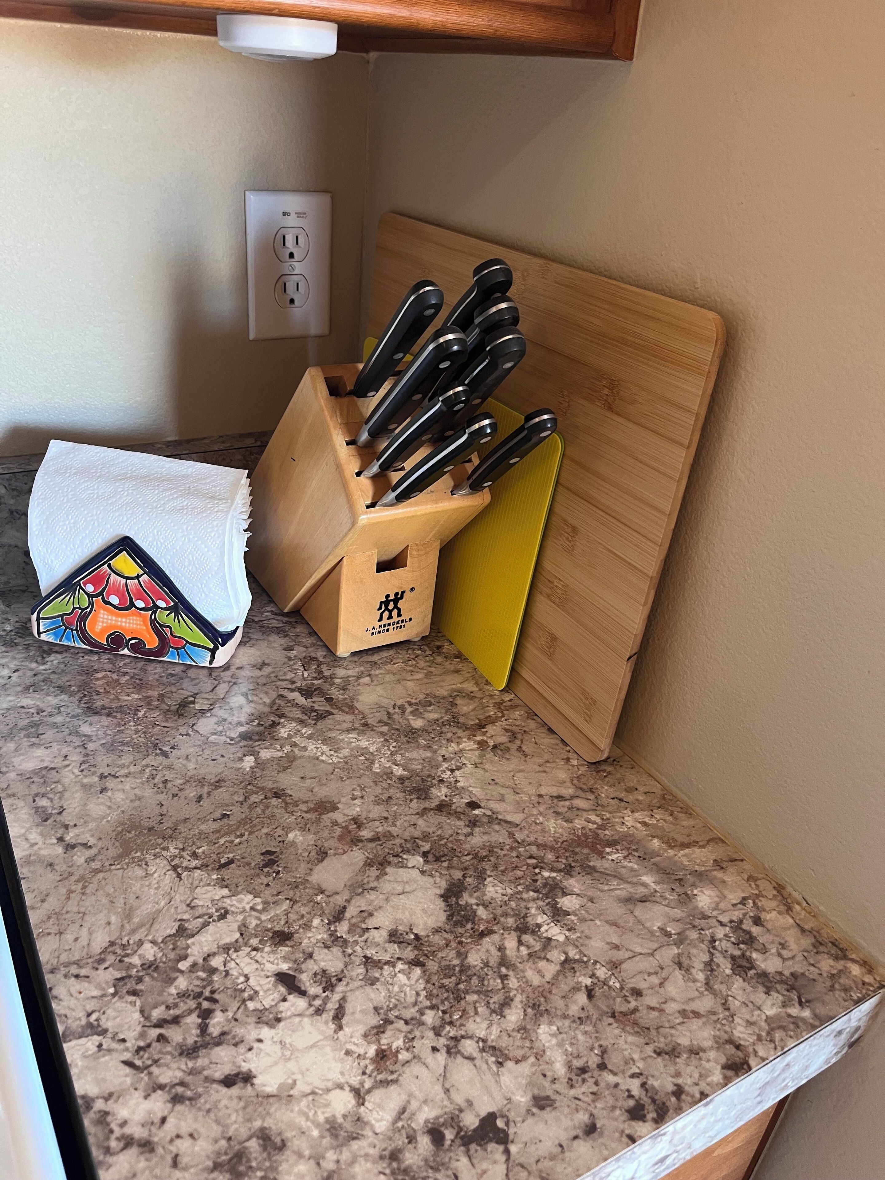 A kitchen counter with a knife block, a cutting board, and a colorful box.