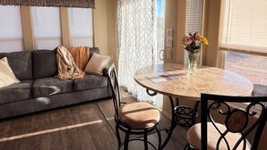 A living room with a sofa, chairs, a round table, and a window with curtains.