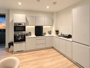 A modern kitchen with built-in appliances, a countertop with a toaster, and a view of the outdoors.