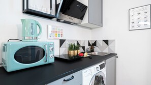 Eine moderne Küche mit einer türkisblauen Mikrowelle, einer Kaffeemaschine, einem Spülbecken und einem Geschirrspüler.