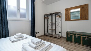 A bedroom with a bed, two towels, a wardrobe, and a mirror. - Italianway Easy - Andrea del Sarto 32 (Milan)