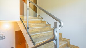 Eine Treppe mit Glastrennwand und Holzvertäfelung, die zu einer oberen Etage führt.