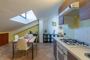 Une cuisine dotée d’une lucarne, un coin repas avec des chaises, un îlot de cuisine et une cuisinière.
