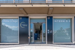 Un bâtiment doté de grandes fenêtres, une enseigne indiquant « Design italien » et une porte portant l’inscription « INTERNI 5.0 ».