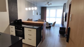 Eine moderne Küche mit schwarzer Arbeitsplatte, weißen Schränken und einem Essbereich mit einem Holztisch und Stühlen.