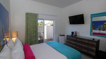 A bedroom with a bed, a dresser, a television, and a sliding glass door leading to an outdoor area.