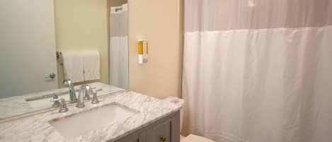 A bathroom with a marble sink, a toilet, and a shower curtain.