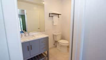 A bathroom with a sink, mirror, toilet, and towel rack.