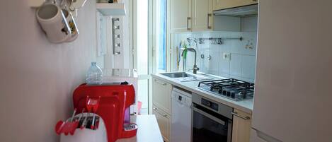 Una cocina con un refrigerador Bosch, un tostador rojo, un lavavajillas y una estufa a gas.