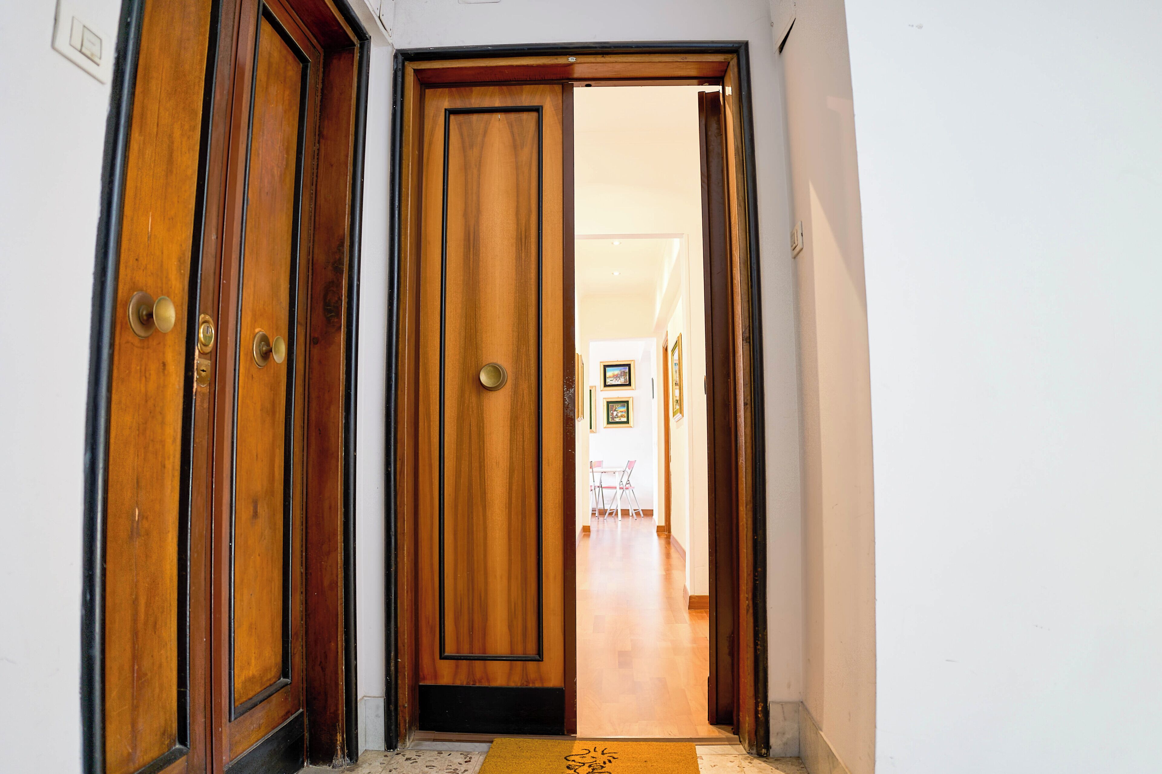 Una puerta de madera con picaporte y felpudo en la entrada.