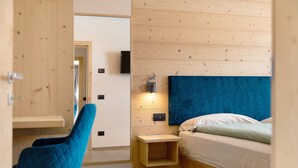 A bedroom with a bed, a nightstand, a chair, and a wall-mounted light fixture. - Chalet 'Arnica' with Mountain View, Balcony and Wi-Fi (Livigno)