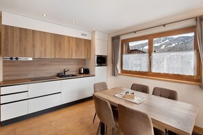 Eine moderne Küche mit Holzschränken, einer Mikrowelle und einem Essbereich mit Tisch und Stühlen.