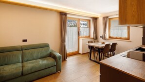 A compact living space with a sofa, dining table, chairs, and a kitchenette. - Chalet 'Genziana' with Mountain View, Balcony and Wi-Fi (Livigno)