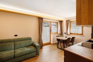 Ein gemütlicher, kompakter Wohnbereich mit einer Couch, Esstisch, Stühlen und einer Küchenzeile.