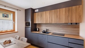 A modern kitchen with dark cabinets, a wooden countertop, and a window with a view. - Chalet 'Genziana' with Mountain View, Balcony and Wi-Fi (Livigno)