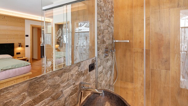 A modern bathroom with a glass shower enclosure, a marble sink, and a wooden vanity. - Chalet 'Genziana' with Mountain View, Balcony and Wi-Fi (Livigno)
