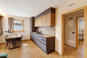 Eine moderne Küche mit Esstisch, Holzschränken und einem Fenster.