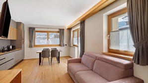 Ett modernt vardagsrum med en soffa, ett matbord, stolar och en tv.