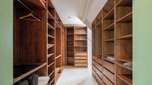 A walk-in closet with wooden shelving and a herringbone floor.