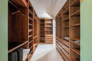 Un dressing accessible sans porte, avec des étagères en bois et un parquet en chevrons.
