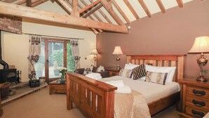 Een slaapkamer met een houten bed, twee nachtkastjes, een raam met gordijnen en een open haard.
