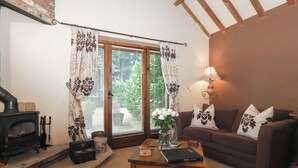 Een gezellige woonkamer met een open haard, een bank, een salontafel en een lamp.