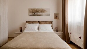 Ein Schlafzimmer mit einem großen Bett, zwei Nachttischen, einem Wandbild und transparenten Vorhängen.