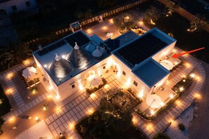 Luchtbeeld van een hotel met een zwembad op het dak, meerdere eetgelegenheden en buitenverlichting.