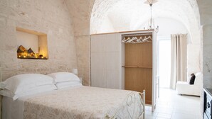 A bedroom with a bed, a wardrobe, and a hanging clothes rack. - Apulian Charm STELLA (Martina Franca TA)