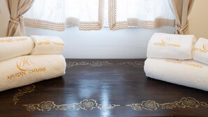 A room with a large window covered by beige curtains, a wooden floor with floral patterns, and three towels with 'APULIAN CHARME' branding. - Apulian Charm STELLA (Martina Franca TA)