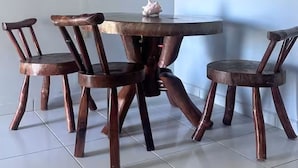Un rincón comedor con una mesa redonda y cuatro sillas de madera.