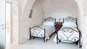 Een kamer met twee bedden, een klein nachtkastje met een lamp en een witte deur.