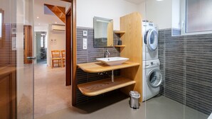 Un bagno moderno con lavandino integrato, uno specchio, una lavatrice e un cestino.