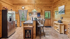 L’intérieur d’un chalet en bois comprend une cuisine, un coin repas et une horloge murale.