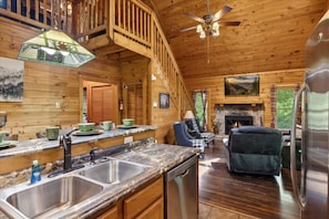 L’intérieur d’un chalet en bois comprend une cuisine, un coin repas et une cheminée.