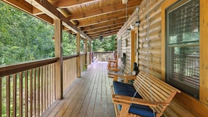 Une véranda en bois avec une balustrade, un banc et une fenêtre.