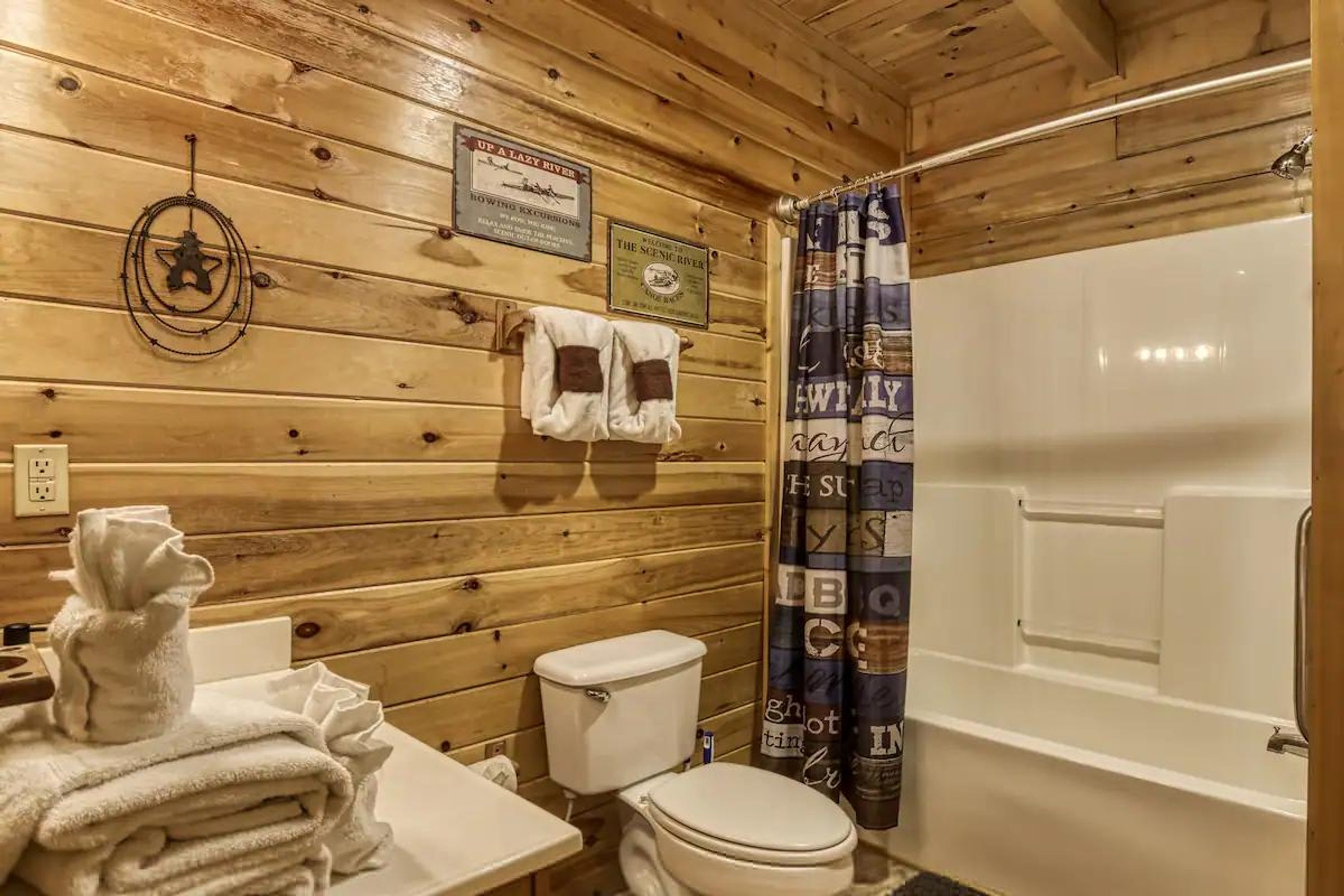 A wooden cabin bathroom with a toilet, sink, and bathtub.