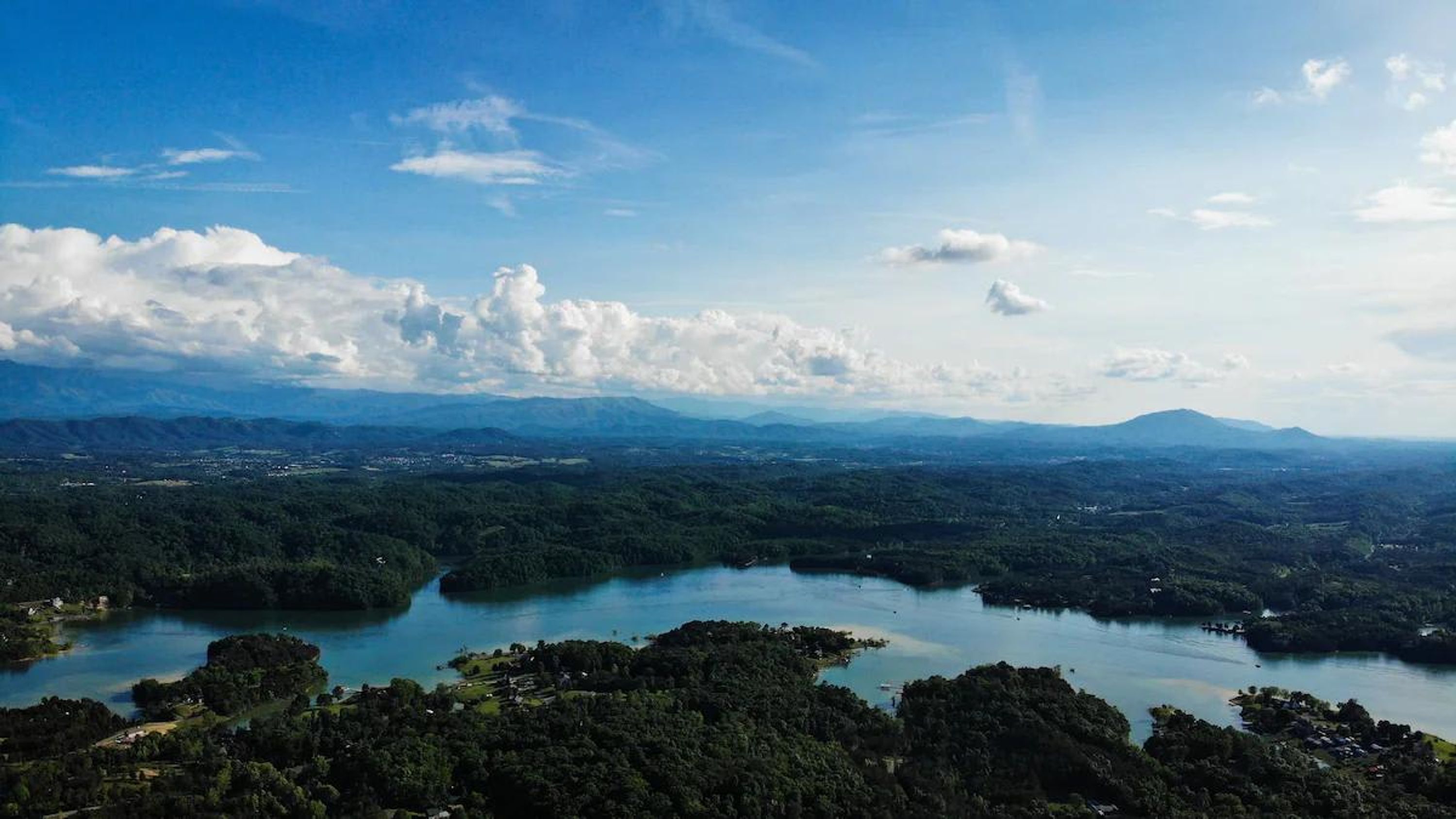 A panoramic view of a mountainous landscape with a lake and scattered buildings.