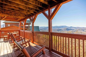 A wooden deck with benches and tables, overlooking a mountainous landscape. - Breezy Ridge Cabin by Beyond Expectations With Hot Tub (Sevierville)