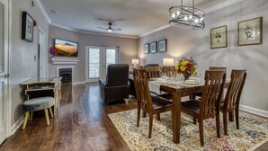 A dining area with a wooden table, chairs, a chandelier, and framed artwork on the walls. - Mountain View Condo by Beyond Expectations (Pigeon Forge)