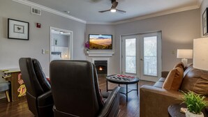 A living room with a fireplace, a television, and a ceiling fan. - Mountain View Condo by Beyond Expectations (Pigeon Forge)