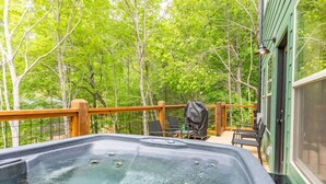 Un bain à remous sur une terrasse en bois, avec vue sur une forêt.